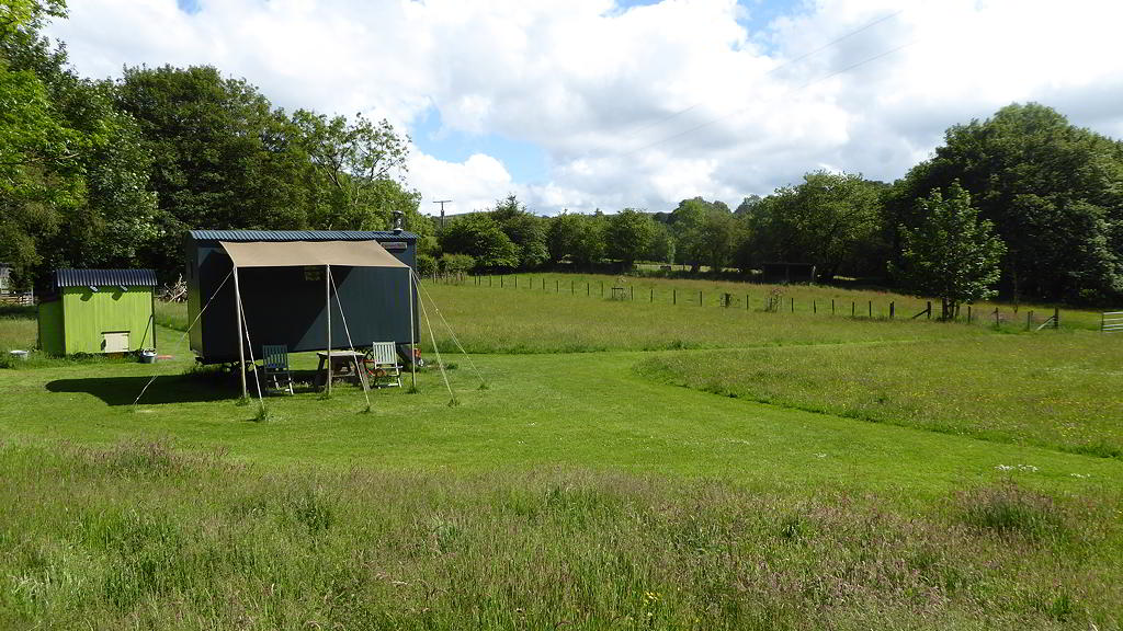 View of the Hygge Hut with Canopy, lavatory hut and the Meadow